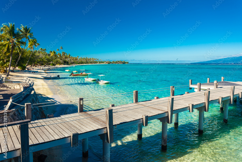 Little jetty and boat on tropical beach with amazing water, Moorea, Tahiti