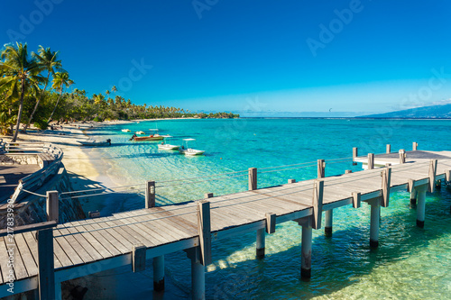Little jetty and boat on tropical beach with amazing water  Moorea  Tahiti