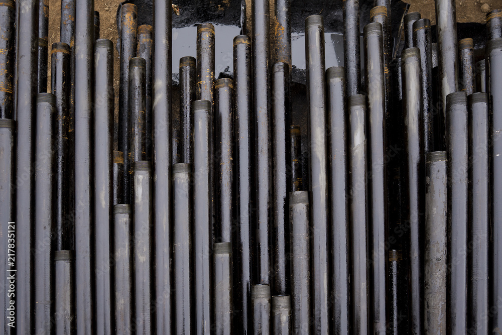 Obraz premium Oil Drill pipe. Rusty drill pipes were drilled in the well section. Downhole drilling rig. Laying the pipe on the deck. View of the shell of drill pipes laid in courtyard of the oil and gas warehouse.