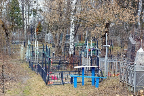 An old cemetery with crosses and fences in dry grass and trees photo