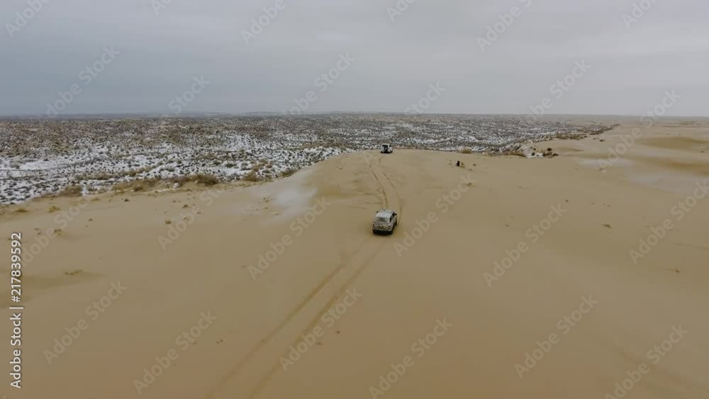 Aerial view of suvs moving through the snow-covered desert in winter. Western Kazakhstan, Mangyshlak Peninsula. Aerial view of suvs moving through the snow-covered desert in winter. Western Kazakhstan, Mangyshlak Peninsula.