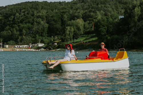 Couple in love enjoying boating in the lake. Portrait of young man and woman pedal boating on the river.
