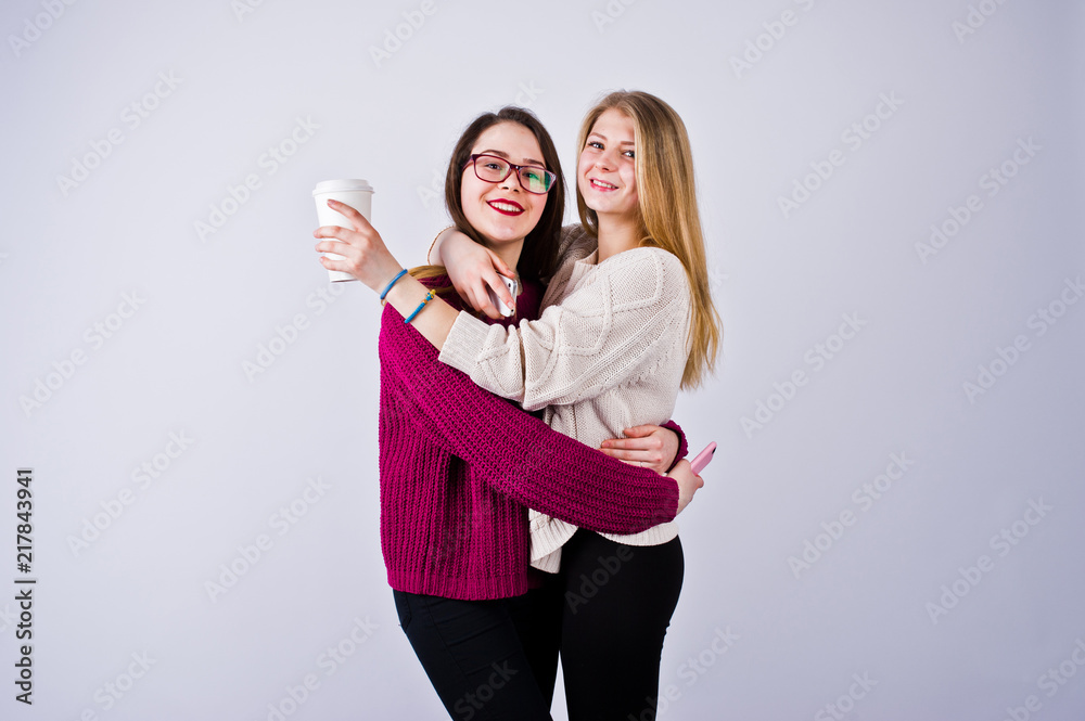 Portrait of two female friends in cherry dresses posing with a coffee in the studio. Portrait of two female friends in cherry dresses posing with a coffee in the studio.