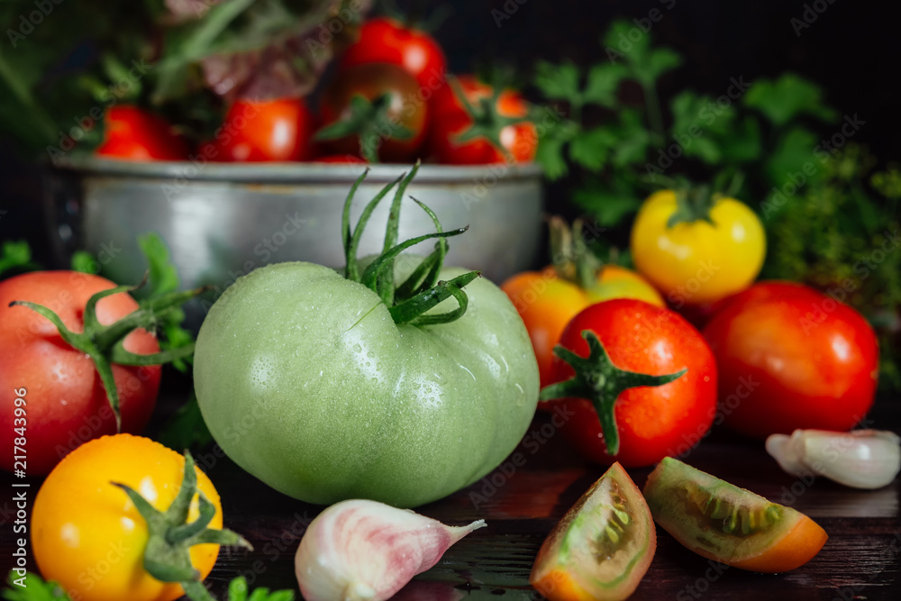 Fresh tomatoes and parsley, dill, garlic on a dark background in a rustic kitchen and wooden utensils still life with copy space Fresh tomatoes and parsley, dill, garlic on a dark background in a rustic kitchen and wooden utensils still life with copy space