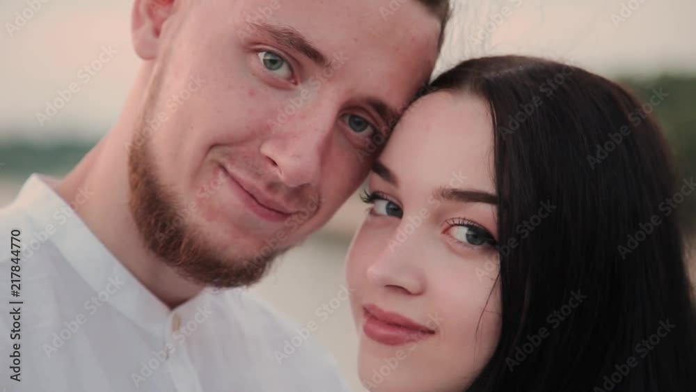 A loving couple is standing on a bridge against a blue sky. A loving couple is standing on a bridge against a blue sky.