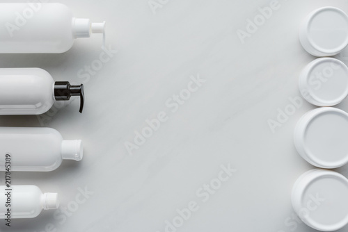 top view of bottles of cream and lotion on white surface, beauty concept