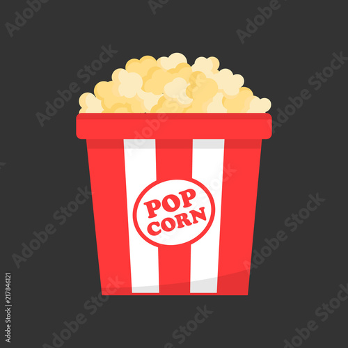 Red and white striped paper box full of popcorn. Salty, butter or cheese cinema snack on grey background.