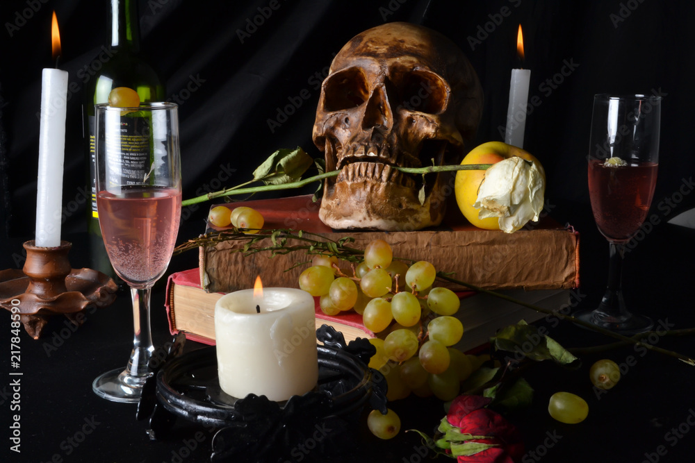 Naturaleza muerta con una calavera con rosas, libros, frutas, vino y velas sobre un fondo oscuro Naturaleza muerta con una calavera con rosas, libros, frutas, vino y velas sobre un fondo oscuro