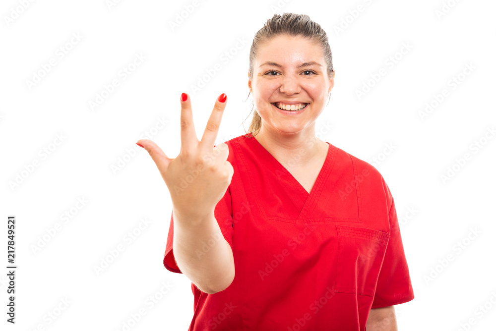 Young medical nurse wearing red scrub showing number three gesture. Young medical nurse wearing red scrub showing number three gesture.