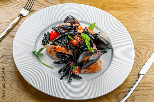 Delicious Italian strozzaperti black squid ink pasta with shrimp, mussels and other seafood. Plate of classic healthy food. Top view shot. © Maxim Khytra