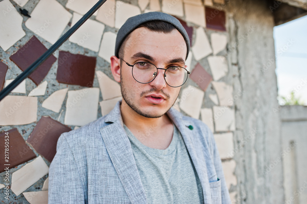 Obraz premium Dreamer stylish macho man in gray suit, hat and glasses posed on the roof.