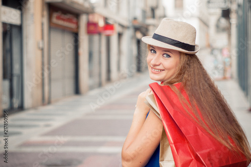 Cute girl with hat and the shopping bags shopping in the city. Closeup portrait with free space for text. Shopping in Europe.