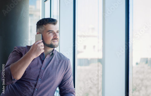 Man talking on the phone at the window in the office