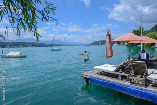 Sunchairs on wooden pier and view of alpine lake Worthersee photo