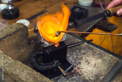 Goldsmith melting down and molding metal with torch equipment to manufacture jewelry