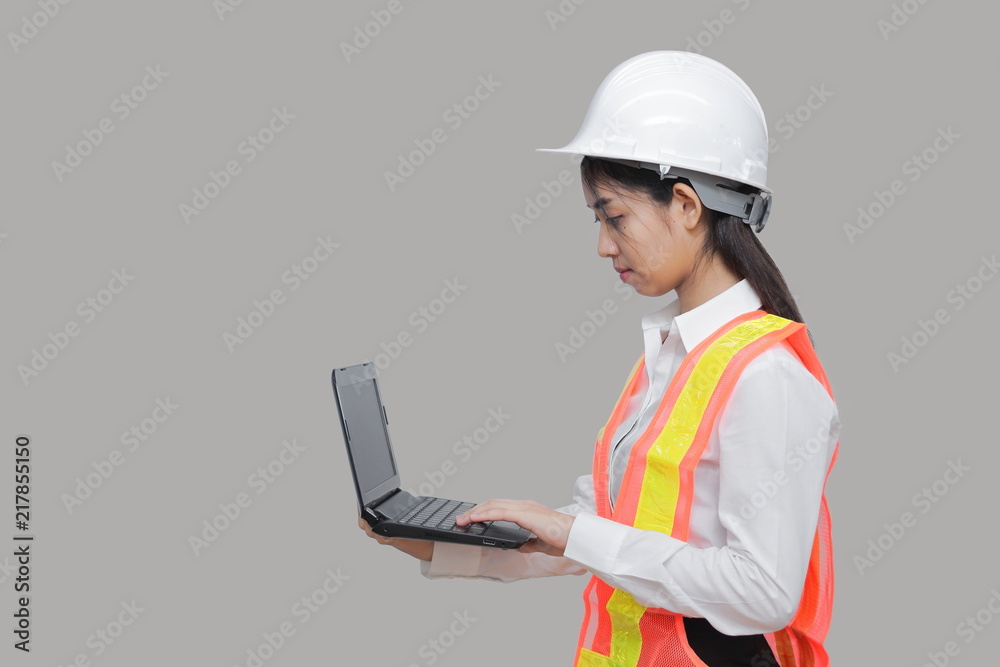Beauty confident young Asian worker with safty equipment carrying laptop on gray isolated background.