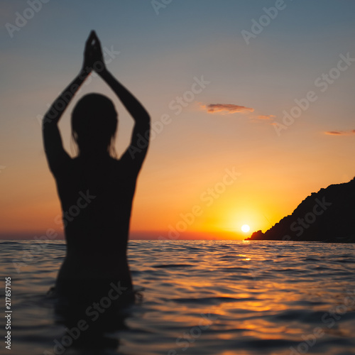yoga pose woman sunset silhouette in sea. Ocean bathing at dawn