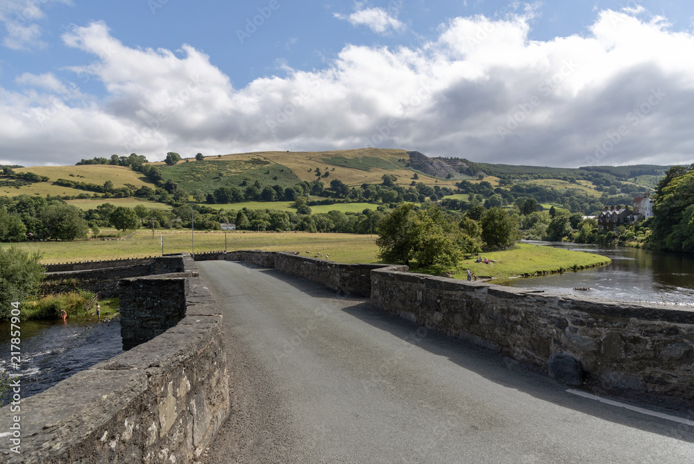 An old stone arched bridge over The River Dee flowing through the Vale of Llangollen, Carrog, Denbighshire, North Wales, UK