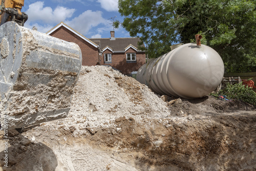 A Excuvator crawler digging a trench for an underground tank on a housing development in Hampshire, England, UK