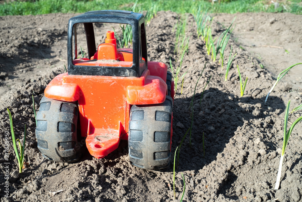 red tractor with black wheels, toy car on the field red tractor with black wheels, toy car on the field