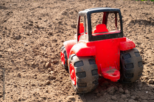 rear view of a red tractor made of plastic  a tractor on a field of dry brown