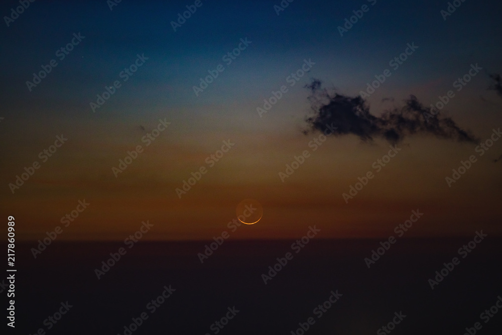 Young Moon photographed from southern hemisphere above the ocean / sea horizon.