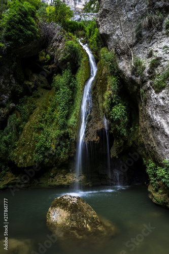 Cascada que cae sobre un río con una roca en el Nacedero del Urederra