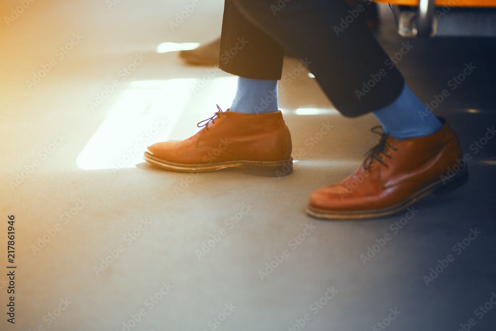 Businessmans shoes. Elegant brown leather shoes and blue socks worn by  businessman on subway train. Stock-Foto | Adobe Stock