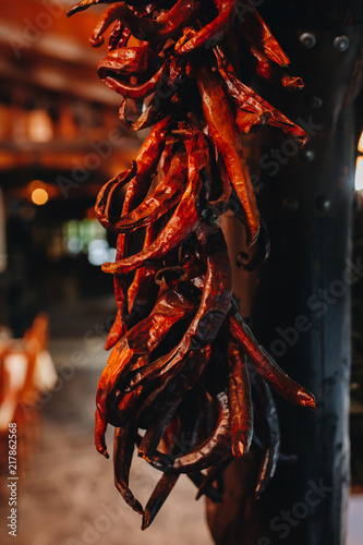 a bunch of hanging dried chili peppers on a wooden pole.