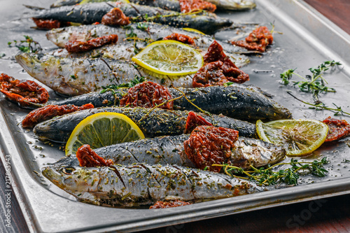 Raw sardine fish on a baking tray. Cooking of delicious seafood meal in an  oven. Close-up shot. photo