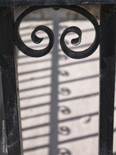 Silhouette of antique cast iron railing with beautiful shadow on the ground. Selective focus, blurred background.
