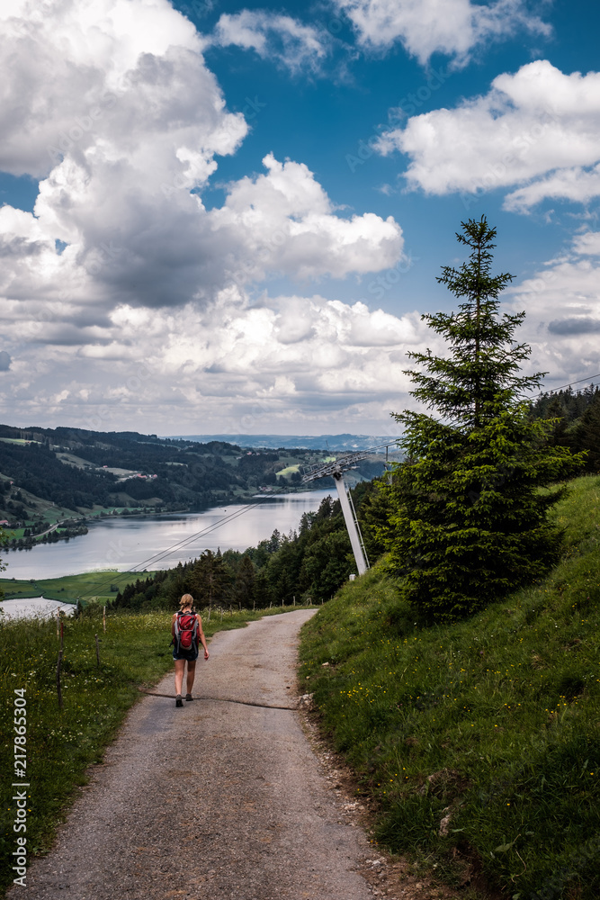 Wanderin auf Weg mit Alpsee im Hintergrund, Allgäu