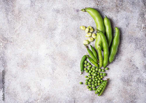 Fresh green peas and beans on light background