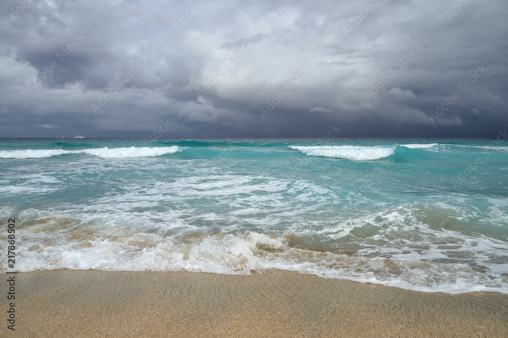 coast of the Atlantic Ocean during a storm, waves on the sand, motor yacht on the horizon, low clouds, Varadero, Cuba