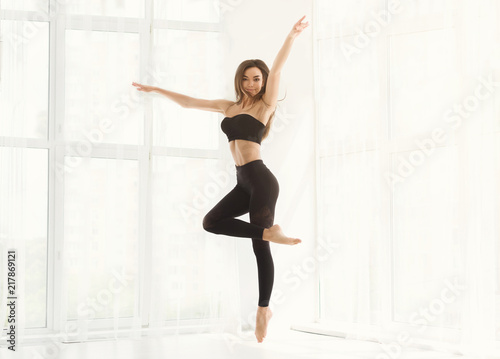 Beautiful graceful woman dancing in white studio