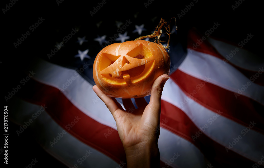 pumpkin halloween in hand against the background of the American flag