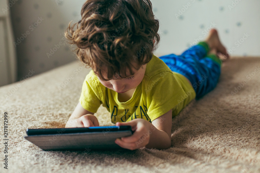 Toddler boy staring at tablet. Education, gadget, dependency, technology, addiction, child eyesight, raising children concept - obrazy, fototapety, plakaty 