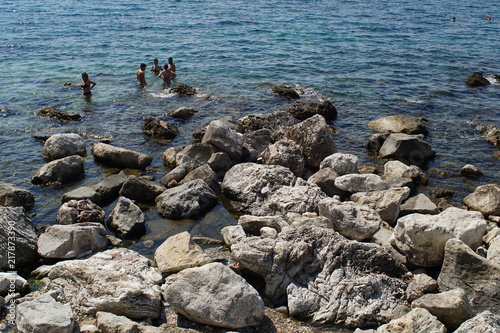 Swimmers at the rocky bay with giant boulders