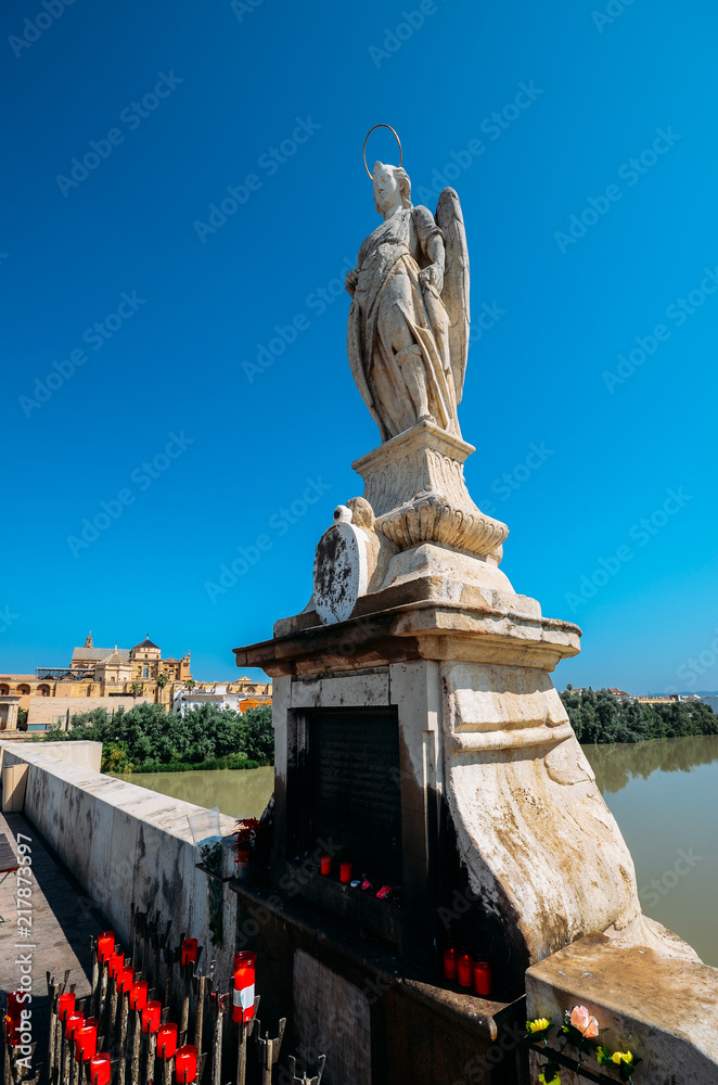 Fototapeta premium Virgin Mary statue on famous Roman bridge of Cordoba across Guadalquivir River. Present structure of bridge dates from Moorish reconstruction in VIII centur
