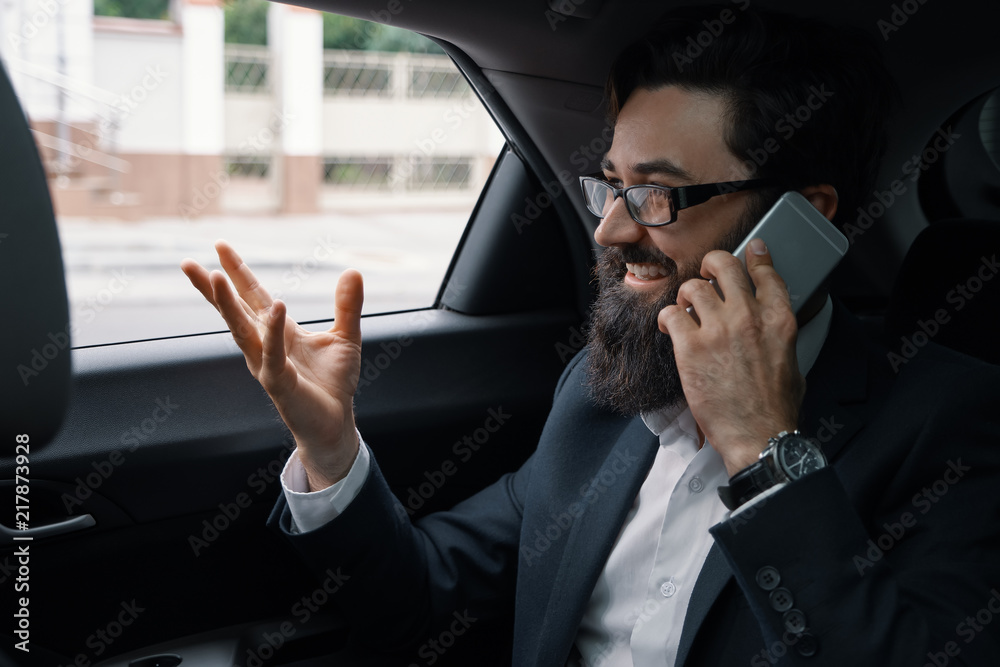 A businessman while traveling by car in the back seat using a sm A businessman while traveling by car in the back seat using a sm