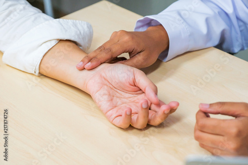 Medical examination. The doctor examines the patient's heart rate by holding his wrist.
