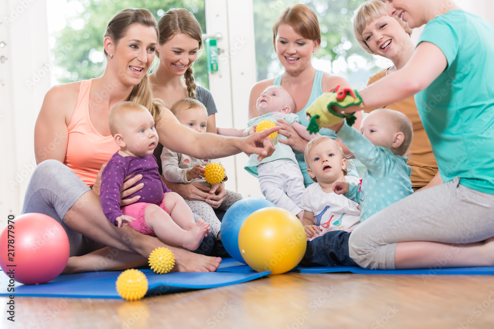 Fototapeta premium Young women in mother and child group playing with their baby kids