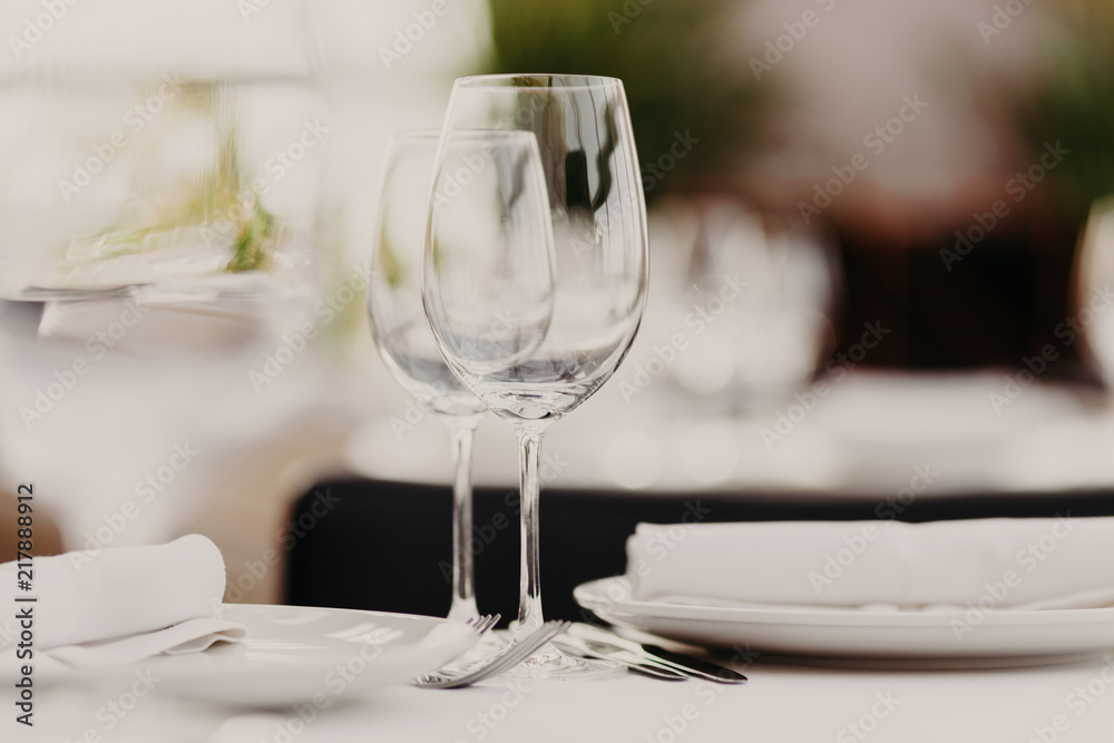 Wedding table set for banquet. Glasses and plates served on table. Dinner setting. Luxury cutlery. Festive event. Horizontal shot. Blurred background. Wedding table set for banquet. Glasses and plates served on table. Dinner setting. Luxury cutlery. Festive event. Horizontal shot. Blurred background.