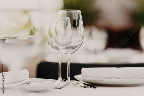 Wedding table set for banquet. Glasses and plates served on table. Dinner setting. Luxury cutlery. Festive event. Horizontal shot. Blurred background. © VK Studio