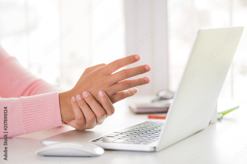 Closeup woman holding her wrist pain from using computer. Office syndrome hand pain by occupational disease. Closeup woman holding her wrist pain from using computer. Office syndrome hand pain by occupational disease.