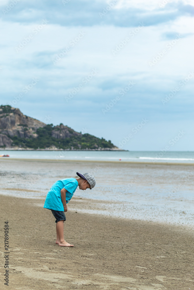 Asian boy walking on the beach by the sea