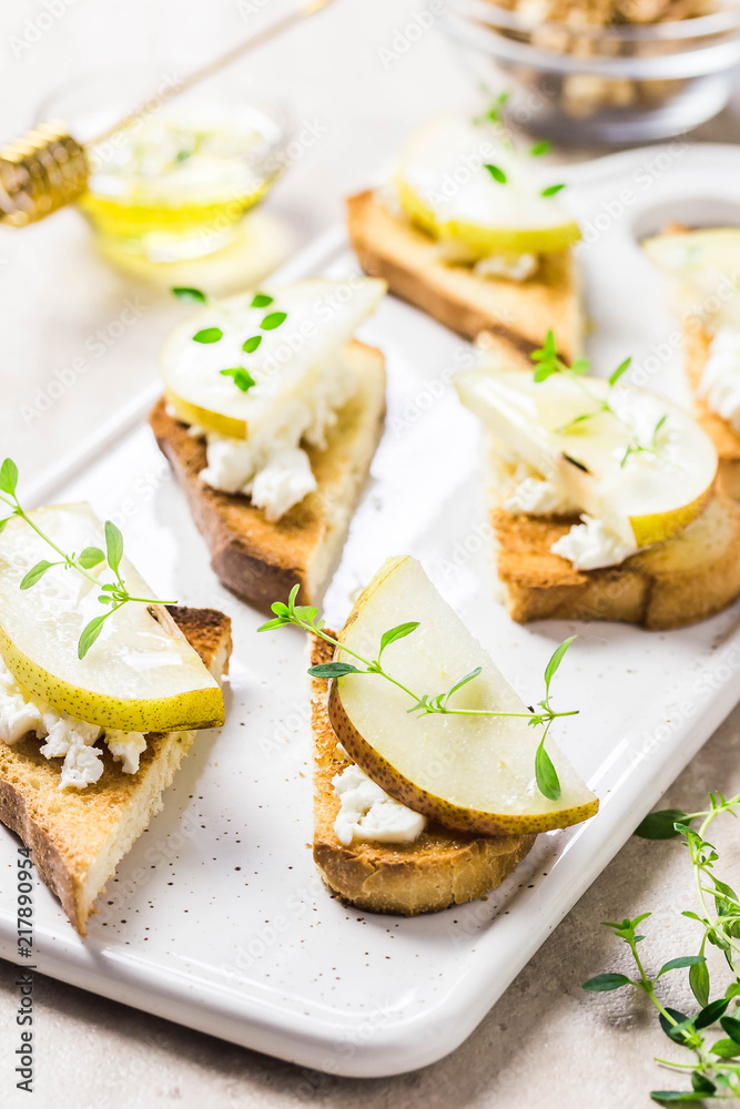 Goat cheese, pear, honey crostini on marble background. Selective focus, space for text.