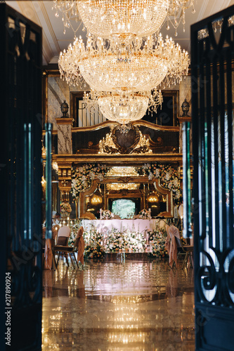 Luxury golden chandeliers hang over rich dinner hall in the restaurant
