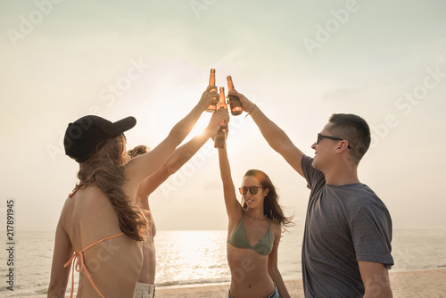 Group of friends celebrating and drinking at the beach in twilight