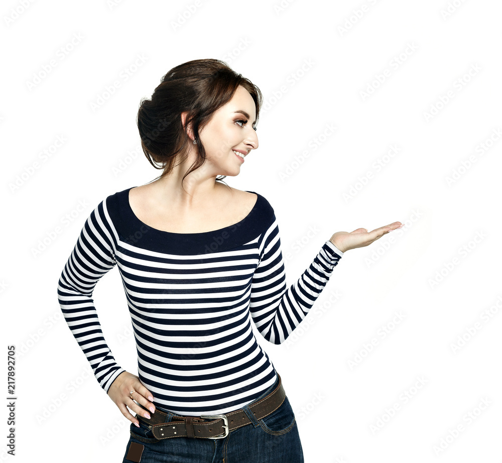 Pretty young woman in striped tight blouse shows pointing hand gesture, isolated on white background. She looks to the left. Pretty young woman in striped tight blouse shows pointing hand gesture, isolated on white background. She looks to the left.